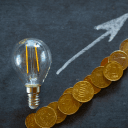 Zdjęcie przedstawia żarówkę, strzałkę w górę oraz monety.